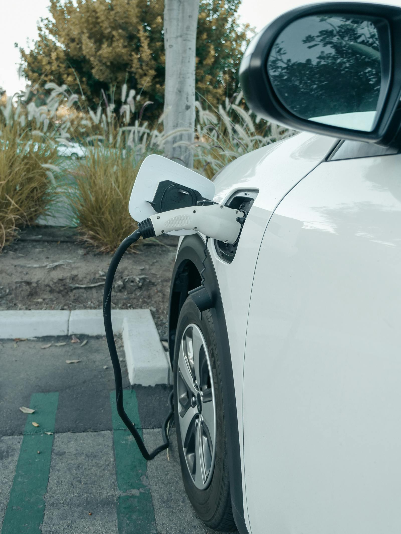Voiture électrique blanche branchée à une borne de recharge sur un parking extérieur